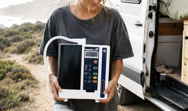 A traveler holding the compact LeveLuk JR IV beside a campervan on the coast